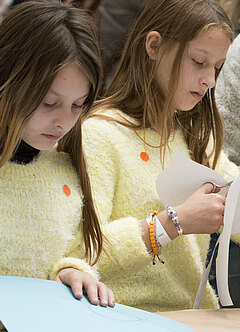Zwei Mädchen schneiden Papier.
