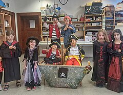 Verkleidete Kinder: Die Jungs als Piraten, die Mädchen als Zauberinnen, als Schiff dient ein umgedrehter Dreieckstisch mit einer Piratenflagge daran