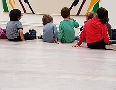 Kinder sitzen auf dem Museumsboden und betrachten Kunst