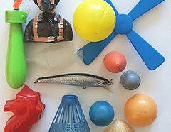 Verschiedene Plastikspielzeuge sowie ein Angelhaken-Fisch als Ensemble arrangiert