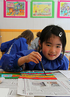 Ein Mädchen malt ein Bild mit bunten Farben.