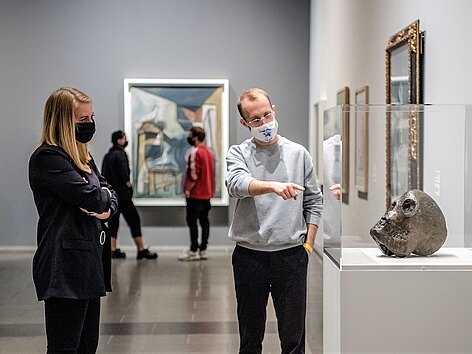 Corona-Pandemie im Museum: Ein Mitarbeiter gibt einer Besucherin Informationen zu einer Skulptur im K20 - beide mit Mundschutz.