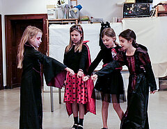 Vier kleine kostümierte Zauberinnen halten jeweils eine Hand zu einer Art Schwur zusammen