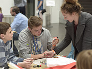 Zwei Jugendliche werken mit unterschiedlichen Materialien an einem Tisch.