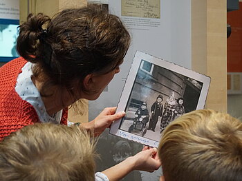 Anna Schlieck zeigt im Rahmen einer Kinderführung Kindern ein Foto von Tom.