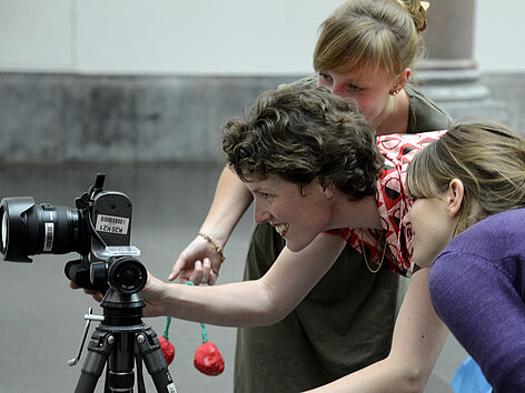 Kinder und eine Mitarbeiterin fotografieren mit einer Digitalkamera.