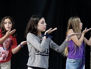 Drei Mädchen auf der Bühne, die pantomimisch pusten