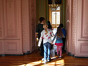 Kinder verlassen durch eine Flügeltür den Gartensaal des Schlosses.
