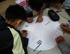 Kinder zeichnen gemeinsam an einem Papier