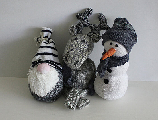 Aus alten Socken entstanden ein Wichtel mit weißem Bart und gestreifter Mütze, ein Elch und ein Schneemann.
