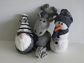 Aus alten Socken entstanden ein Wichtel mit weißem Bart und gestreifter Mütze, ein Elch und ein Schneemann.
