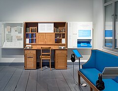 Blick in die Ausstellung mit Schreibtisch und Sofa.