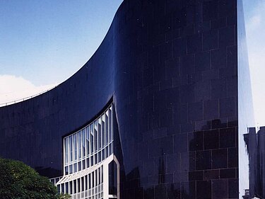 K20: schwarz glänzende, geschwungene Granitfassade am Grabbeplatz, in der Hauptbiegung weiß gerahmte Fensterreihung und scharfkantiger Übergang zur glatten Wandfläche an der Heinrich-Heine-Allee.