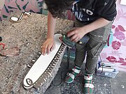 Ein Jugendlicher bearbeitet eines der ausgesägten Motive mit einem elektrischen Handschleifgerät.