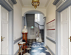 Blick in den Eingangsbereich des Heinrich-Heine-Instituts mit schwarz-weißen Fliesen; links an der Wand steht eine Büste des Dichters und Schriftstellers Heinrich Heine
