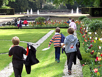 Kinder laufen durch den Schlosspark.