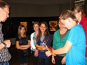 Eine Gruppe von Jugendlichen umringt ein Gruppenmitglied, das eine Kornnatter auf Händen hält.